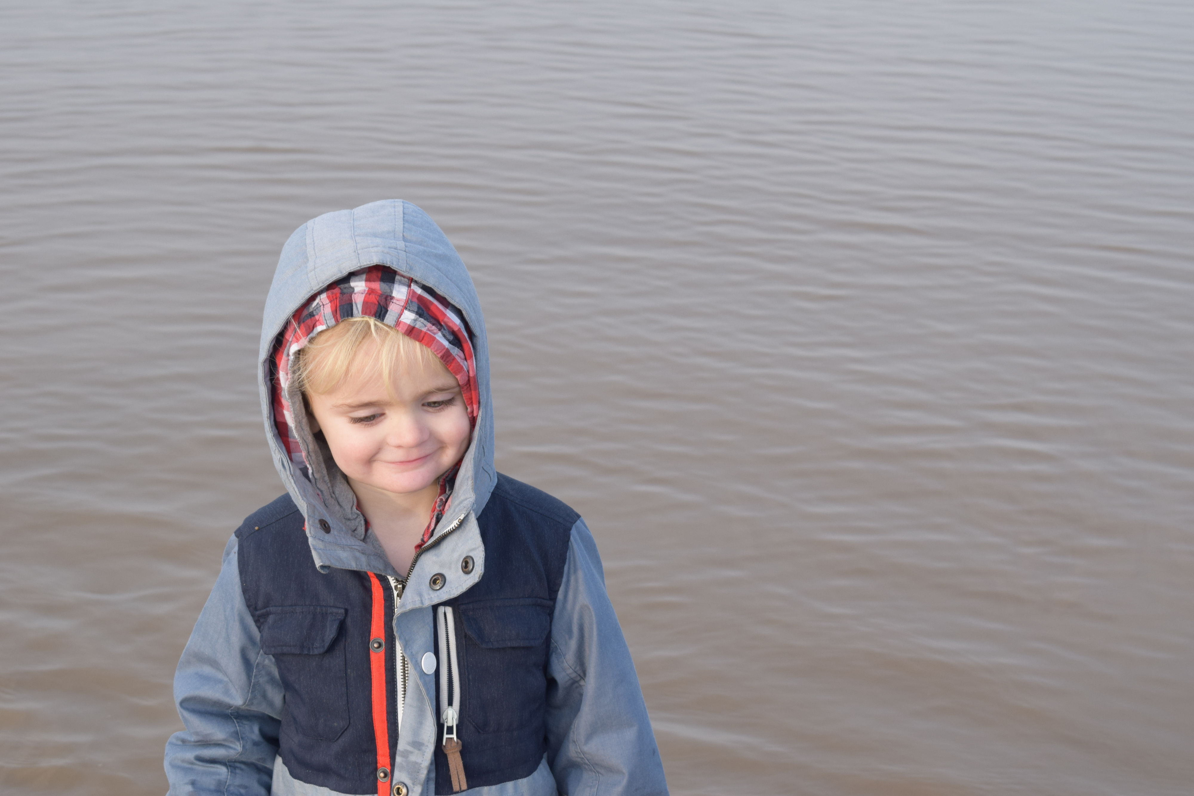 Toddler boy with hood up by sea